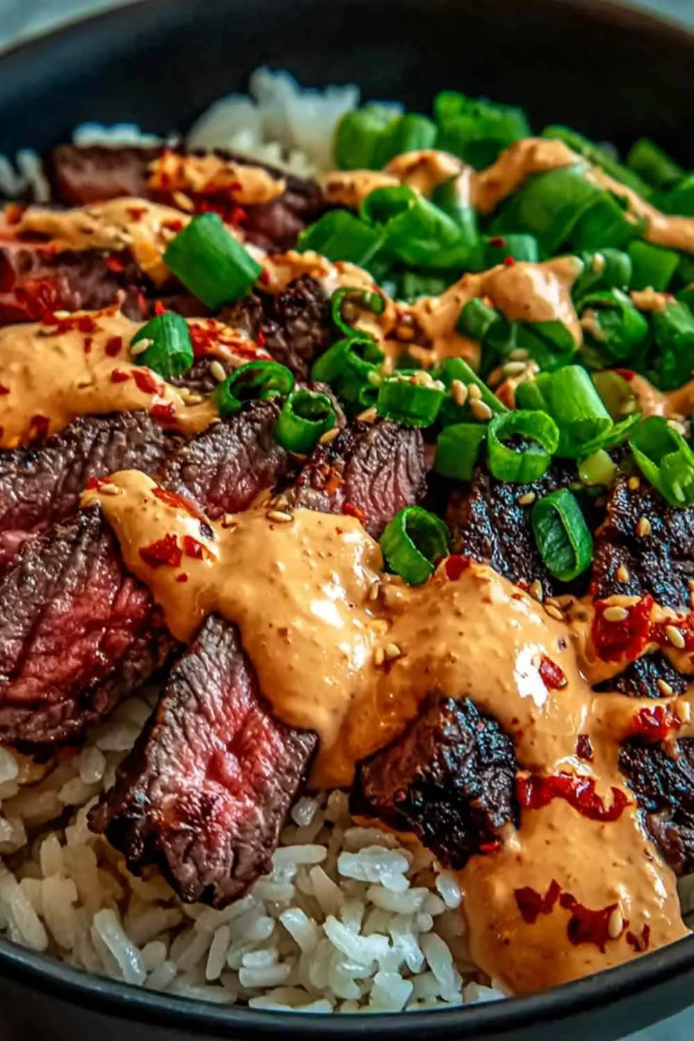 Korean BBQ steak rice bowls with spicy cream sauce on a white table