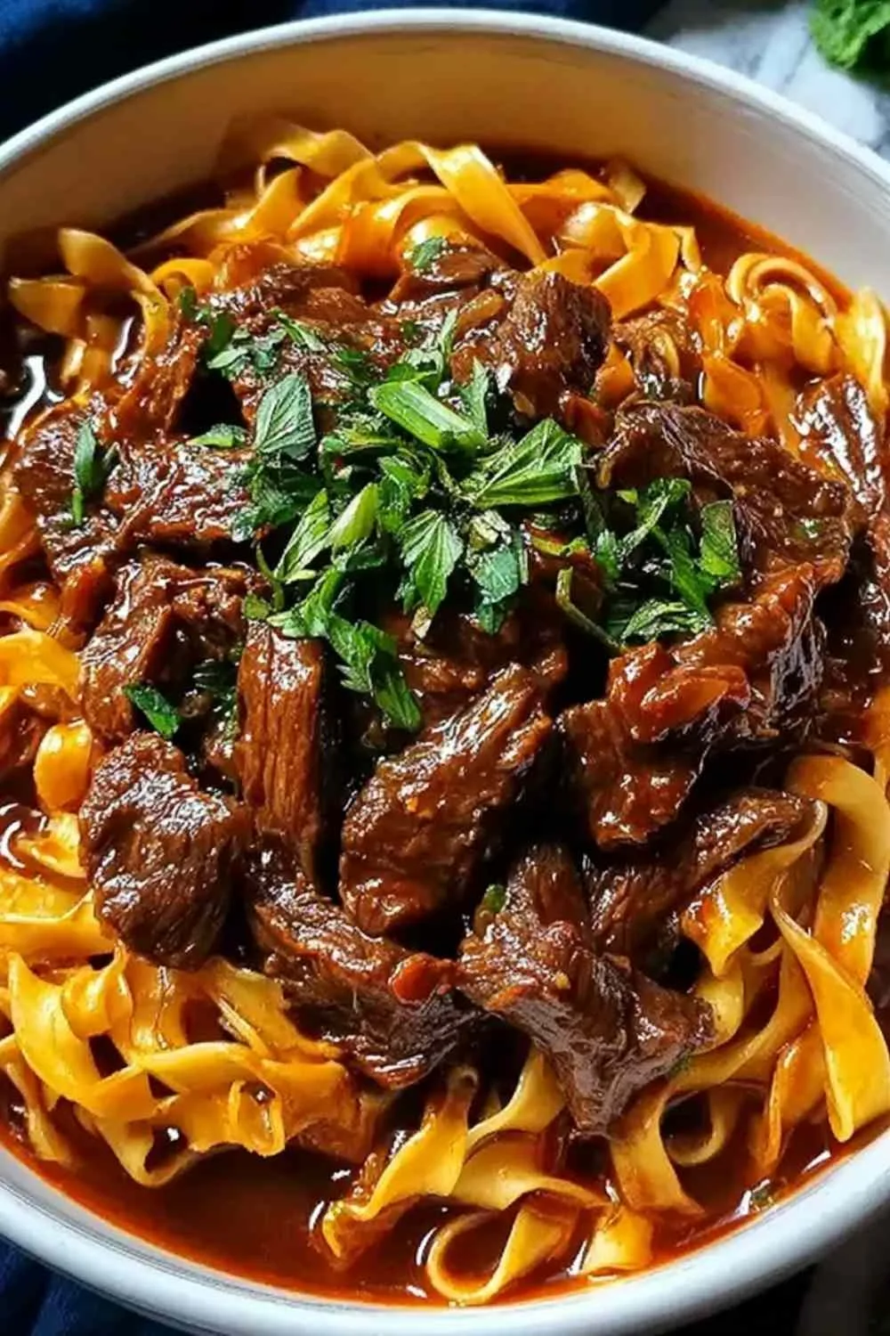 Korean beef noodles in a deep bowl with green onions and sesame seeds