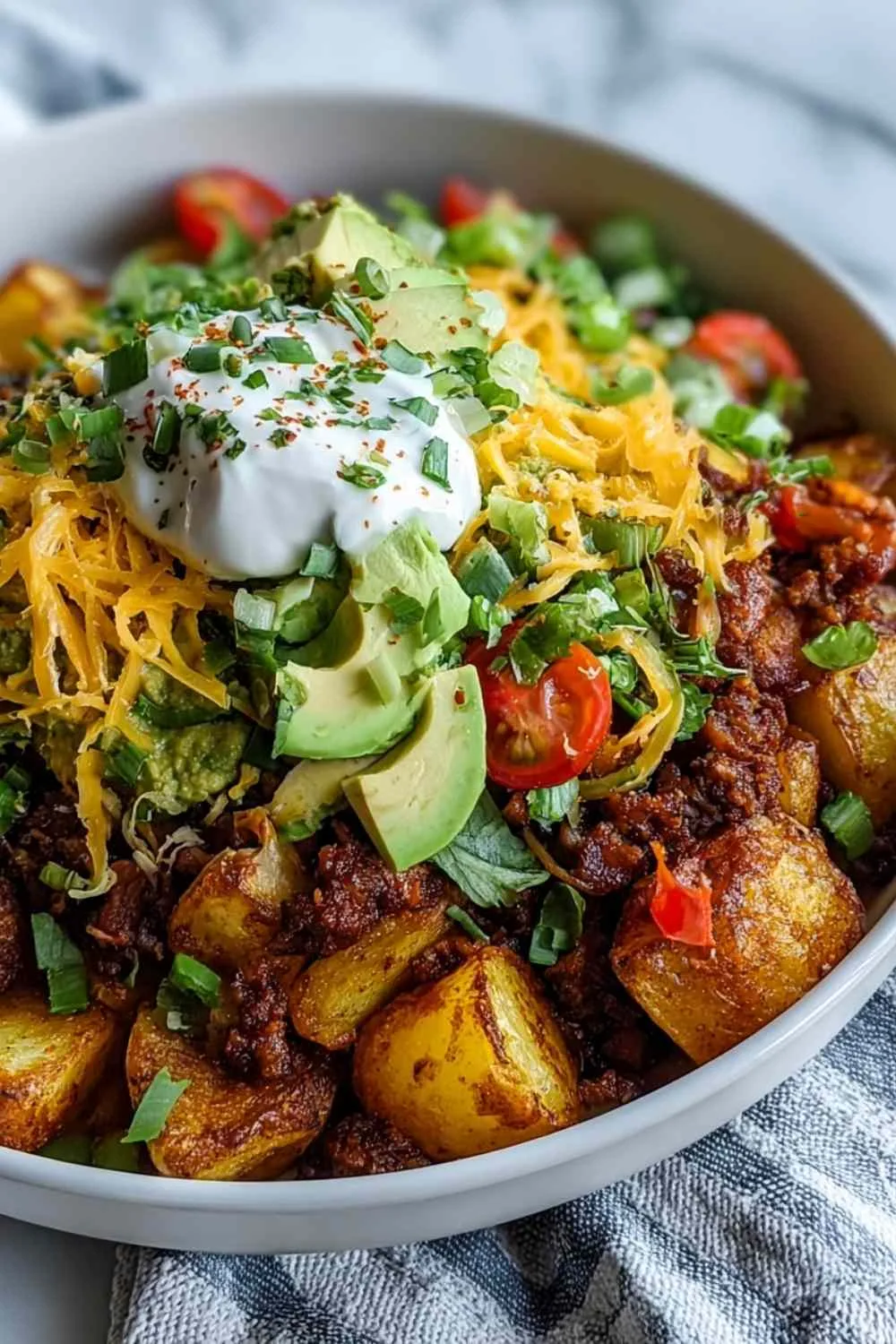 Loaded Potato Taco Bowl with crispy potatoes, ground beef, and fresh toppings served in a white bowl.