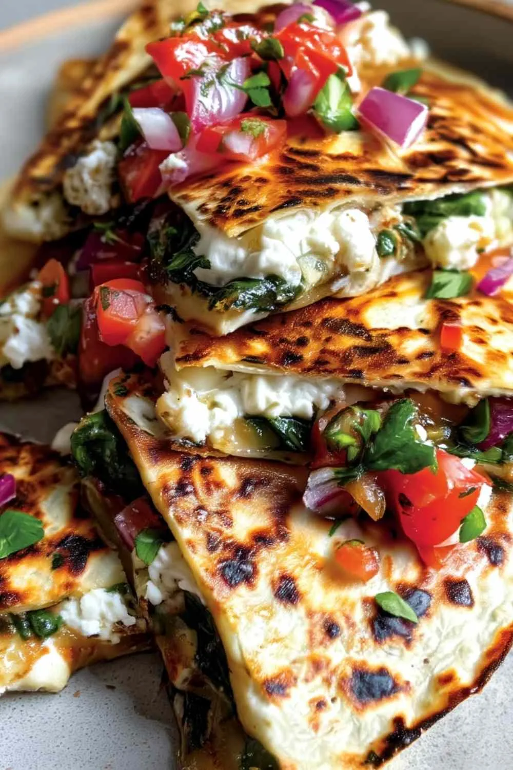 Mediterranean quesadillas with spinach feta mozzarella and red onion on a white plate