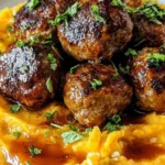 Pork meatballs with sweet potato mash drizzled with bourbon maple sauce on a white plate.