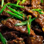 Slow cooker Mongolian beef served over steamed white rice topped with green onions