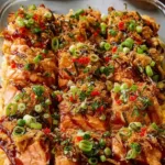 Spicy salmon sushi bake in a white casserole dish topped with avocado cucumber green onion and Kewpie mayo drizzle