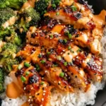 Sticky Chicken Rice Bowls in white bowl with sesame seeds and green onions