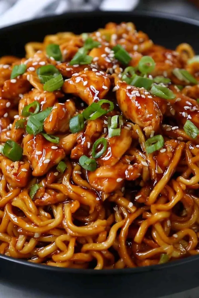 Sticky Garlic Chicken Noodles in a cast iron pan with chopsticks