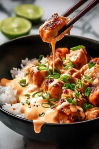 Sweet Chili Chicken Bowl with Coconut Lime Drizzle Magic in a white bowl on a wooden table.