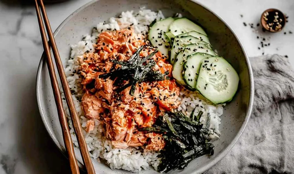 Spicy tuna rice bowl topped with nori, cucumber, and sesame seeds