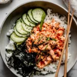 Spicy tuna rice bowl topped with nori, cucumber, and sesame seeds