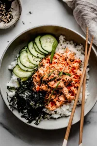Spicy tuna rice bowl topped with nori, cucumber, and sesame seeds