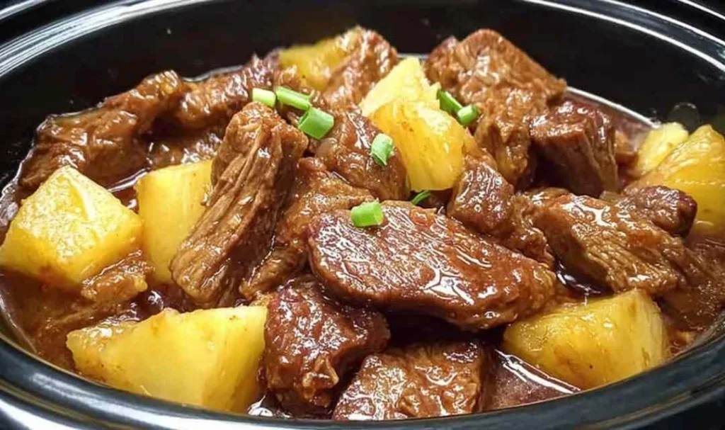 Slow cooker pineapple pork served over jasmine rice with green onion garnish