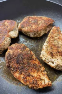 Homemade chicken alfredo with sliced golden chicken breast over creamy fettuccine in a white bowl