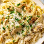chicken alfredo pasta in white bowl with parsley and parmesan