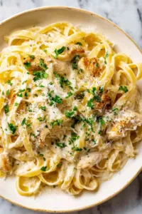 chicken alfredo pasta in white bowl with parsley and parmesan
