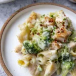 Chicken Alfredo pasta bake with broccoli and melted mozzarella in a white casserole dish