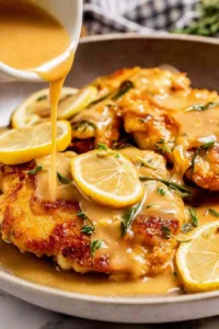 Chicken Francese in a pan with white wine lemon sauce and lemon slices