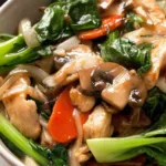 chicken stir fry chop suey in a wok with glossy Chinese brown sauce Close-up of chicken stir fry chop suey cooking in a wok over high heat, showing the thick brown sauce coating the chicken and vegetables. Betty Harper recipe tested in a Midwest home kitchen.