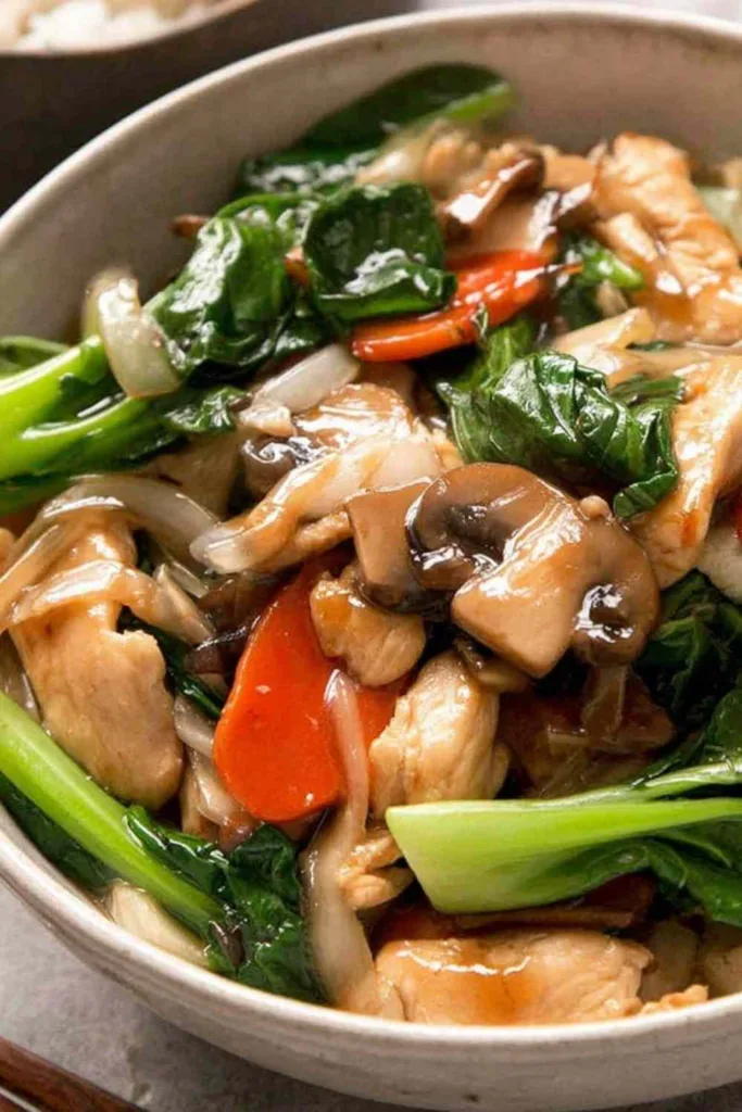 chicken stir fry chop suey in a wok with glossy Chinese brown sauce Close-up of chicken stir fry chop suey cooking in a wok over high heat, showing the thick brown sauce coating the chicken and vegetables. Betty Harper recipe tested in a Midwest home kitchen.