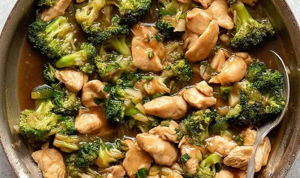 Chicken broccoli stir fry in a wok with glossy sauce over steamed rice
