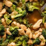Chicken broccoli stir fry in a wok with glossy sauce over steamed rice