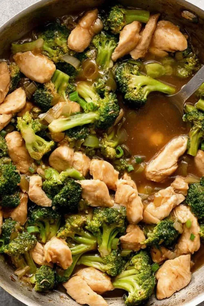 Chicken broccoli stir fry in a wok with glossy sauce over steamed rice