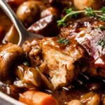 Coq au Vin French chicken stew in a Dutch oven with red wine sauce bacon and mushrooms