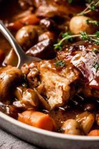 Coq au Vin French chicken stew in a Dutch oven with red wine sauce bacon and mushrooms