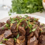 Crock pot steak bites in garlic butter sauce served over creamy mashed potatoes