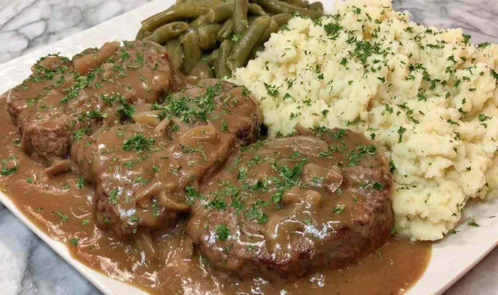 Crockpot cube steaks layered in a slow cooker with onion slices