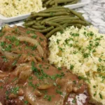 Crockpot cube steaks layered in a slow cooker with onion slices