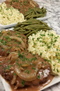 Crockpot cube steaks layered in a slow cooker with onion slices