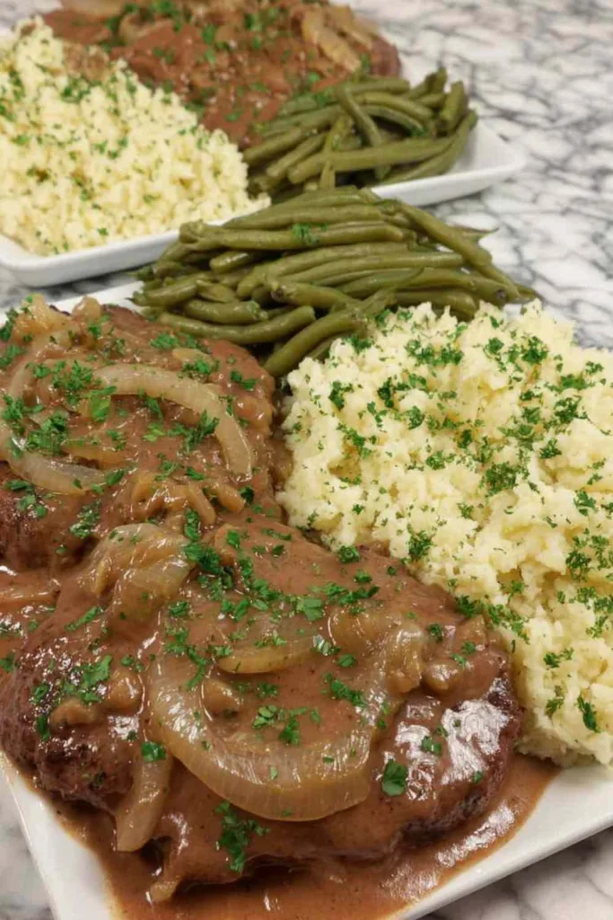 Crockpot cube steaks layered in a slow cooker with onion slices