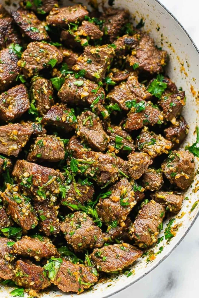 Garlic herb butter steak bites seared in cast iron skillet with fresh parsley