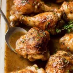 gravy baked chicken thighs and drumsticks in a baking pan with rich dark gravy