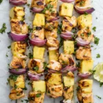 Grilled pineapple chicken kabobs on a white plate garnished with fresh cilantro