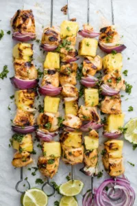Grilled pineapple chicken kabobs on a white plate garnished with fresh cilantro
