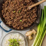 Korean ground beef rice bowls topped with green onions and sesame seeds in a white bowl