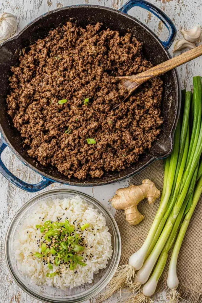 Korean ground beef rice bowls topped with green onions and sesame seeds in a white bowl