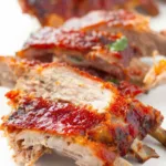 Fall off the bone oven baked ribs glazed with homemade BBQ sauce on a wooden cutting board