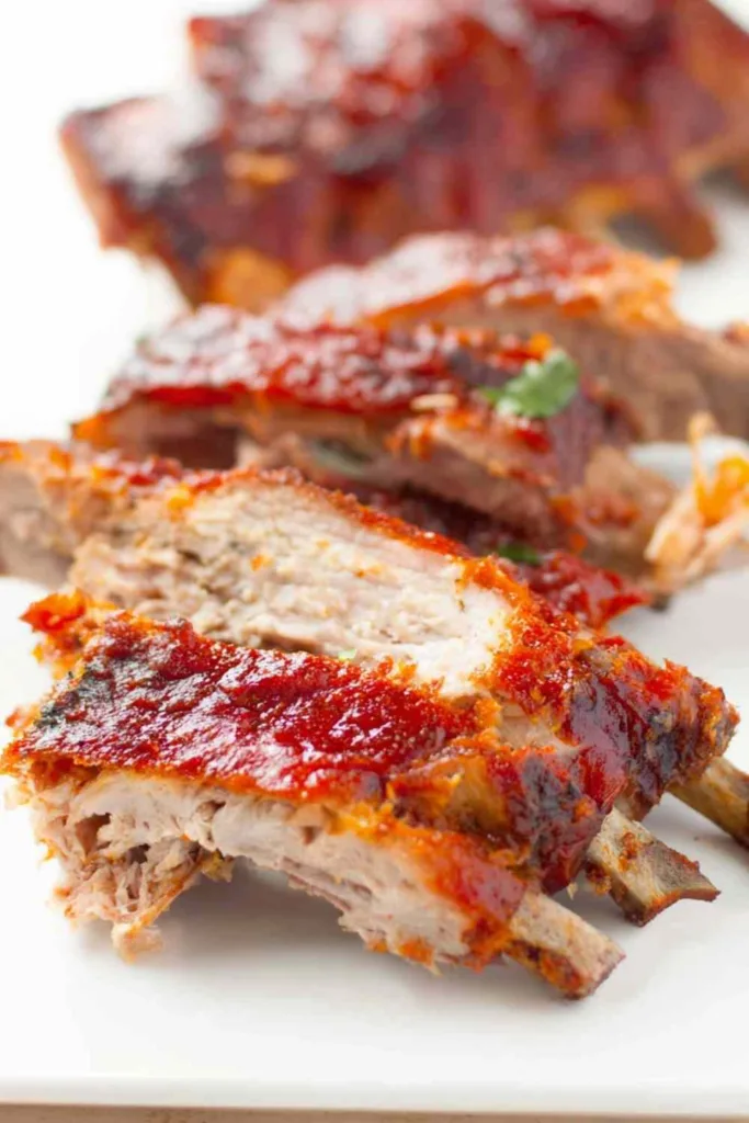 Fall off the bone oven baked ribs glazed with homemade BBQ sauce on a wooden cutting board