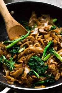 pad see ew thai stir fried noodles in wok caramelized