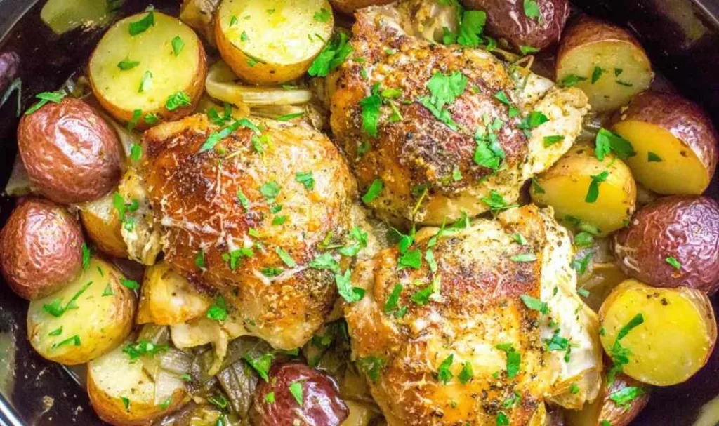 Slow cooker garlic parmesan chicken thighs with baby potatoes garnished with fresh parsley
