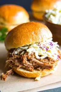 Slow cooker pulled pork piled onto toasted sandwich rolls with creamy coleslaw