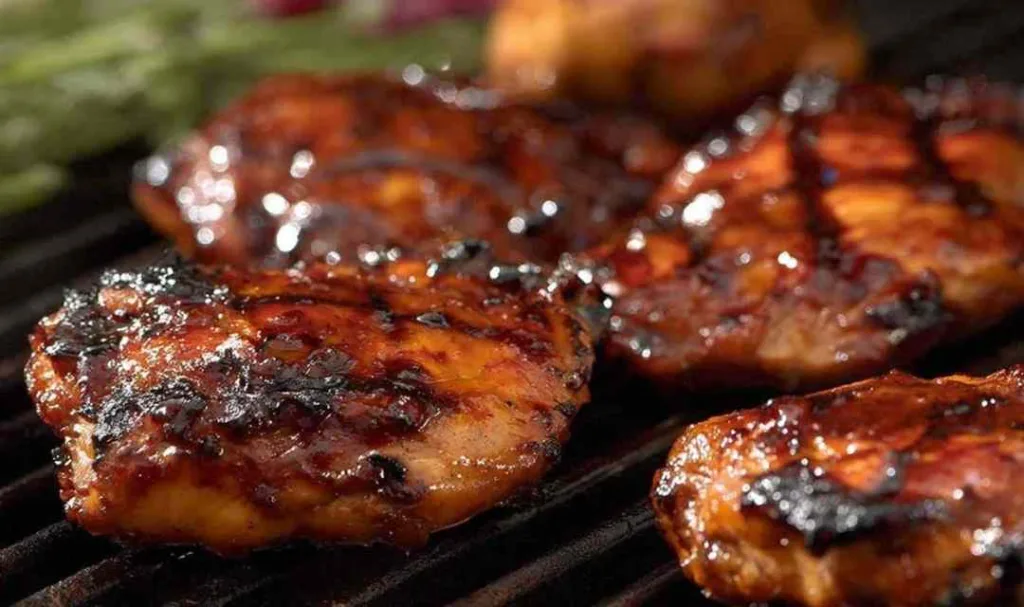 Sticky grilled chicken thighs on a BBQ grill with caramelized glaze