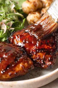 Sticky grilled chicken thighs on a BBQ grill with caramelized glaze