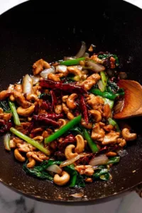 Thai cashew chicken stir fry served over jasmine rice in a white bowl