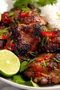 Juicy Thai Grilled Chicken Gai Yang on a white plate with lime wedges