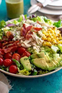 big quick chicken salad in a large bowl with avocado, bacon, and fresh vegetables