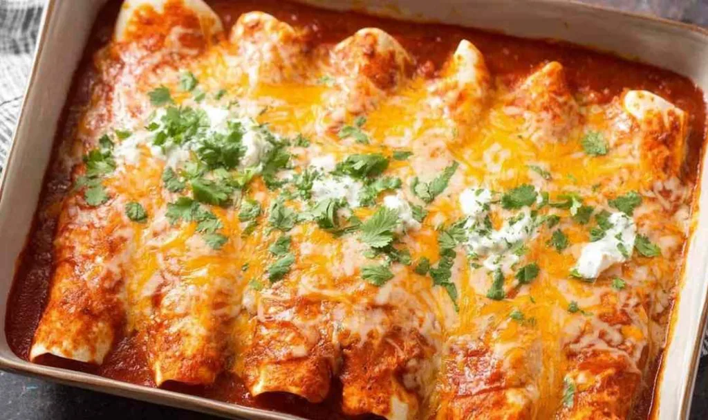 homemade chicken enchiladas in a baking pan with melted cheese and cilantro