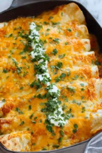 Easy chicken enchiladas in a 9x13 baking dish with melted Mexican cheese fresh from the oven