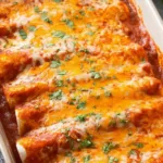 homemade chicken enchiladas in a baking pan with melted cheese and cilantro